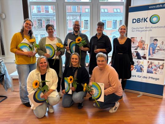 Sieben glückliche Absolvent:innen – und zwei zufriedene Prüferinnen: Marina Kauer, stellv. DBfK Nordwest-Geschäftsführerin (2. Reihe, 1.v.r.) und Kerstin Liekmeier, Organisationsberaterin (2. Reihe, 2.v.r.)